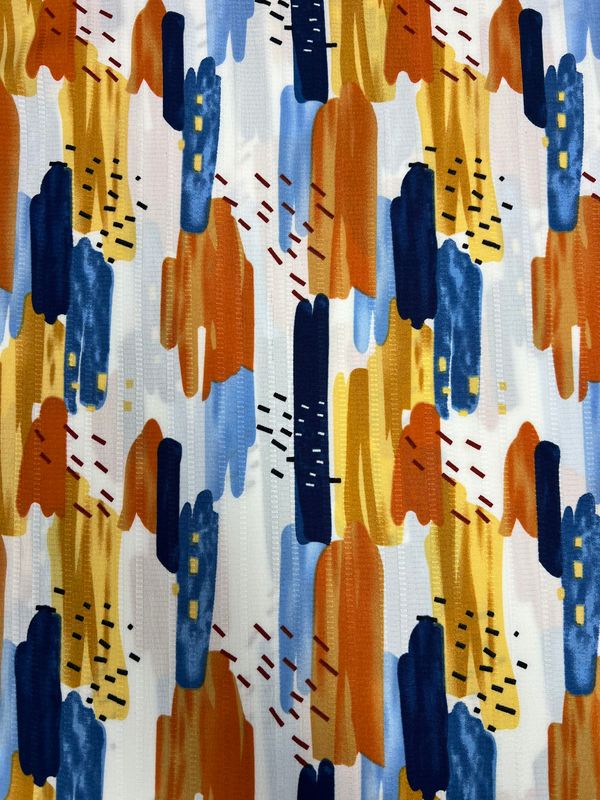 The Textured Deluxe Print - Stroke & Speck 1.0 - 155cm by Super Cheap Fabrics showcases an abstract pattern with vertical brushstrokes in blue, orange, and yellow on a white background. The inclusion of small scattered dashes adds texture and contrast, making this fabric ideal for enhancing any space with its versatility.