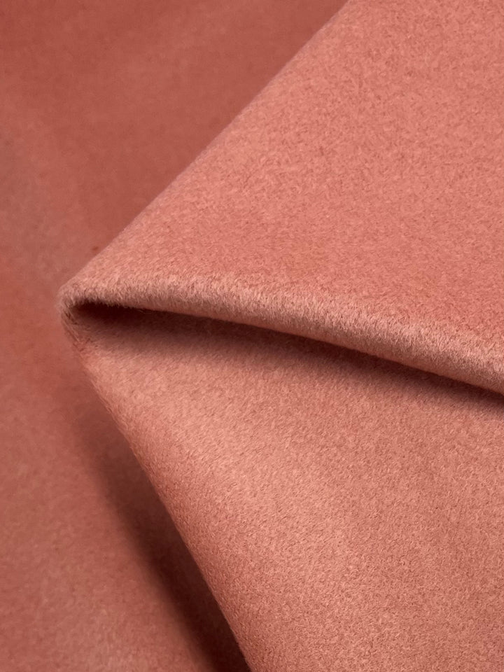 A close-up view of a folded piece of Wool Cashmere - Rosette from Super Cheap Fabrics, showcasing its soft, pinkish-brown hue. The smooth, slightly fuzzy texture of this heavy weight fabric highlights its thick and warm quality, making it ideal for coats or blankets. Dry clean only.