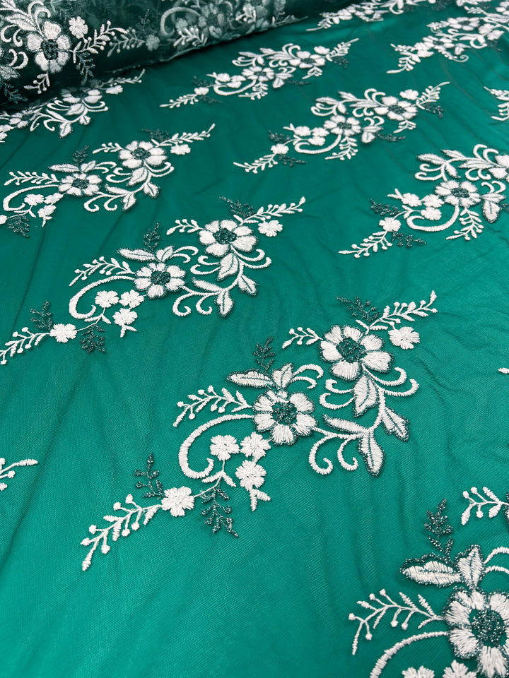 The Embroidered Lace - Aztek by Super Cheap Fabrics is a 150cm fabric in rich teal, featuring intricate white floral embroidery reminiscent of French lace with swirling vine-like designs for a delicate and elegant appearance.