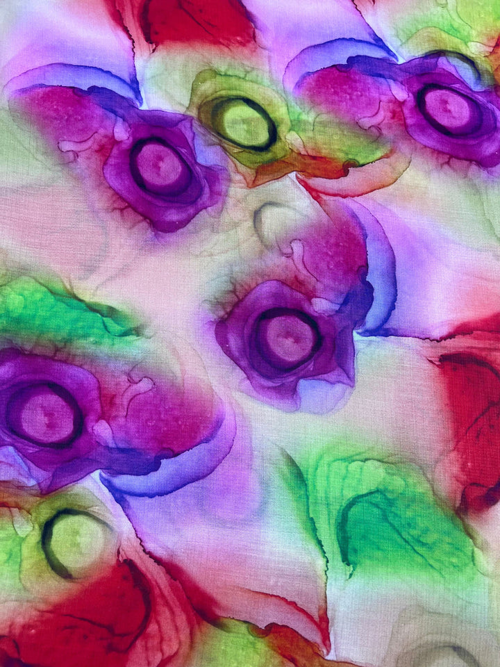 Super Cheap Fabrics' Designer Cotton - Springs features a vibrant abstract watercolor-like pattern with swirling purples, reds, greens, and yellows on a light background. Ideal for luxury sewing projects, this 150cm fabric evokes colorful blooms for lively visual appeal.