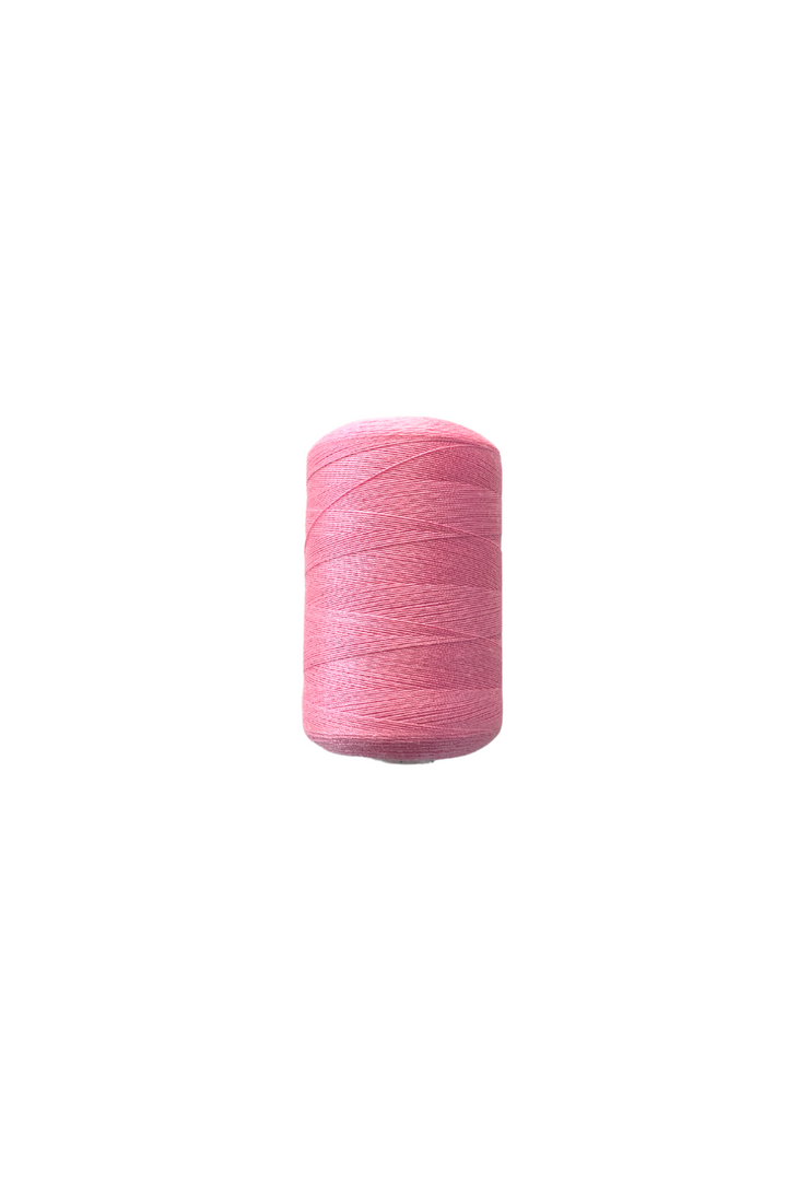 A spool of Super Cheap Fabrics' Thread - Pink is centered on a white background. The spun polyester thread is tightly wound around the spool, creating a cylindrical shape. The image is bright and clear, emphasizing the vibrant color of the 1000-meter-long thread.