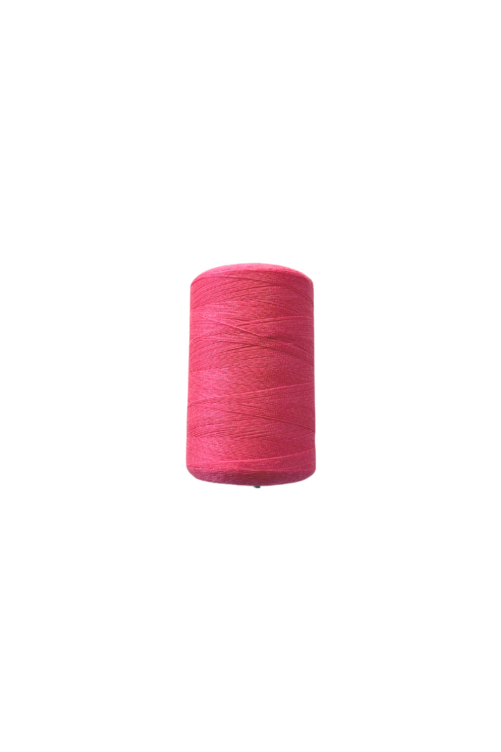 A close-up image showcases a large spool of Super Cheap Fabrics' Thread - Hot Pink, wound tightly and positioned upright against a plain white background. The sewing thread appears neatly aligned, highlighting its vibrant color and smooth texture.