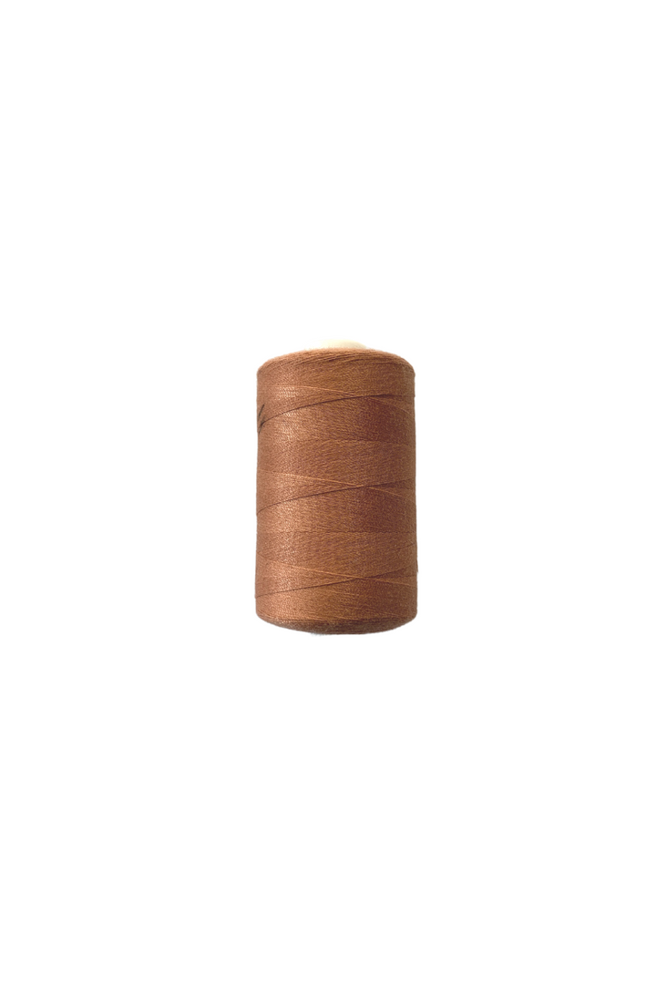 The Thread - Rust by Super Cheap Fabrics is a 40/2 spun polyester brown sewing thread, elegantly displayed on a white background, offering the perfect blend of strength and smoothness for stitching needs.