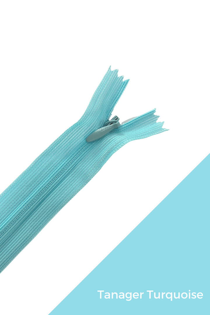 Close-up of an unzipped "Invisible Zip - 30cm - Blues" from Super Cheap Fabrics, set against a white and turquoise background. The zipper, crafted from 100% polyester and labeled "Tanager Turquoise," is partially separated at the top. Its elegant finish enhances its aesthetic appeal.