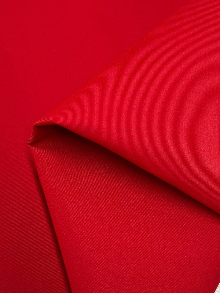 Close-up of a folded vibrant red fabric with a smooth, slightly textured surface. The 100% polyester material is neatly creased, showcasing its ability to hold shape and highlighting its bright, bold goji berry color. The lighting emphasizes the rich hue and subtle sheen of the Delustered Satin - Goji Berry - 150cm from Super Cheap Fabrics.