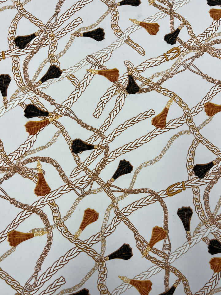 An intricate pattern featuring intertwined gold and bronze chains adorned with tassels in shades of black and brown on a white background. The luxurious design, crafted from designer fabrics by Super Cheap Fabrics, highlights various textures and twists of the chains, making it both decorative and versatile. Introducing the Deluxe Print - Luxe Ties - 150cm!