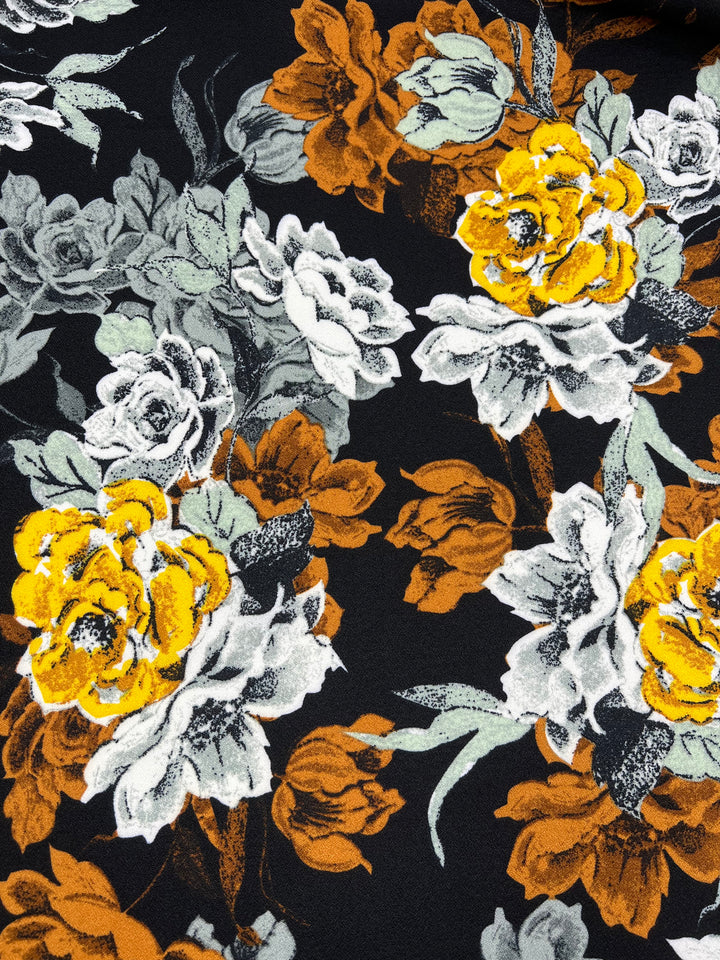 The Super Cheap Fabrics Printed Crepe - Marigoldine 150cm showcases a stylish high-fashion floral design with large flowers in yellow, white, and burnt orange on a black background. Crafted from lightweight polyester, it features green and gray leaves intertwined with the blossoms.