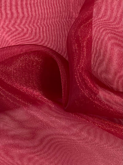 A close-up of the Super Cheap Fabrics' Organza in Burgundy reveals its sheer elegance, with a smooth, wavy texture. The light softly reflects off its surface, highlighting the nylon fabric's delicate transparency and fluidity. This creates graceful folds and evokes a sense of movement across its 150cm width.